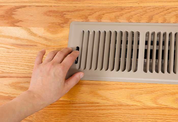 Person touching home air vent. Apex Air, serving Portland OR & Vancouver WA talks about how to improve indoor air quality.