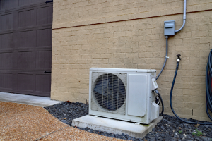 Air Conditioner mini split system next to home with brick wall - Apex Air in Vancouver WA and Portland OR explains how ductless heat pumps work.